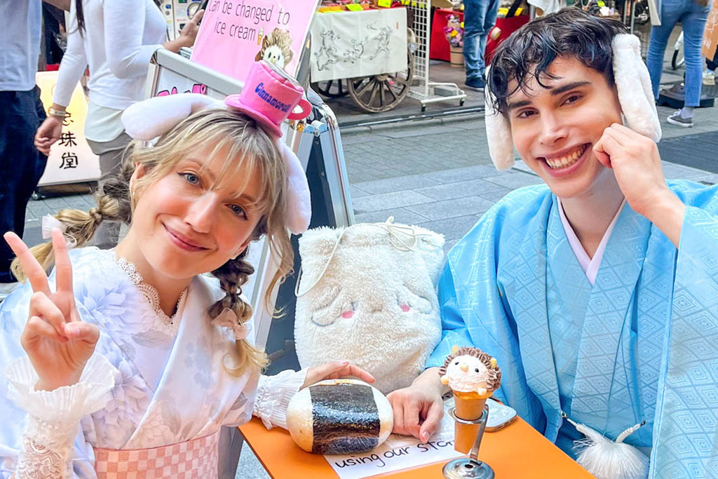 Two people in traditional Japanese attire with a stuffed animal and ice cream cone on a table.